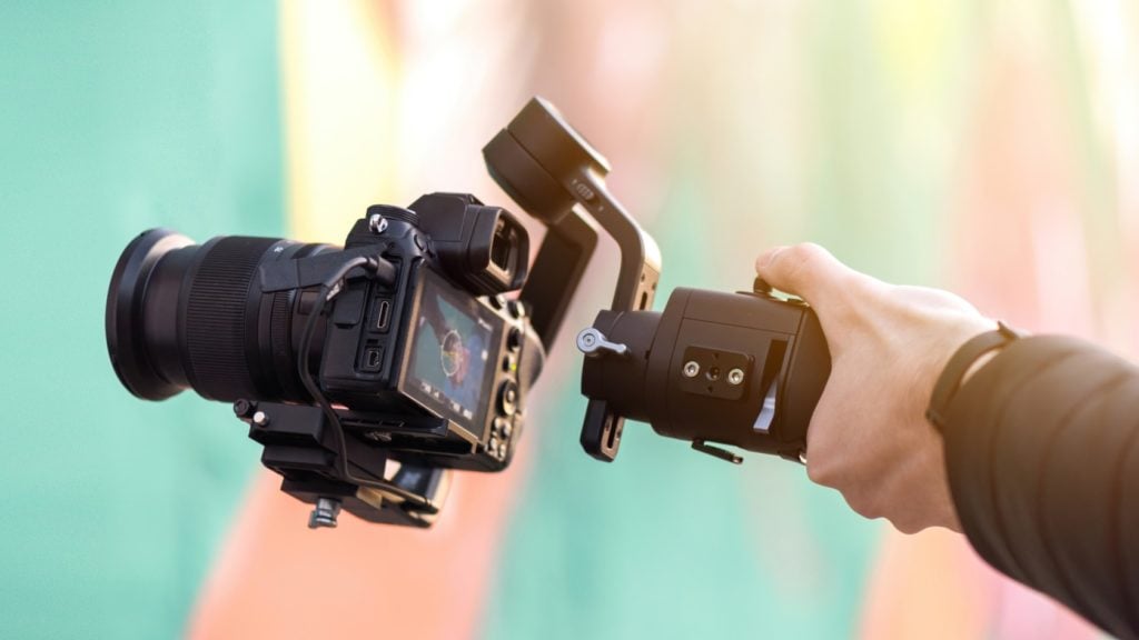 Camera being held by hands over pastel background